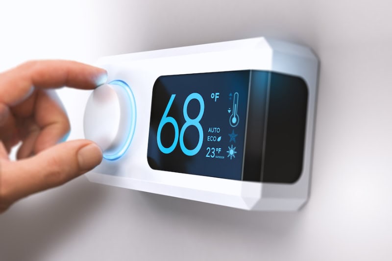 Homeowner adjusting thermostat temperature.