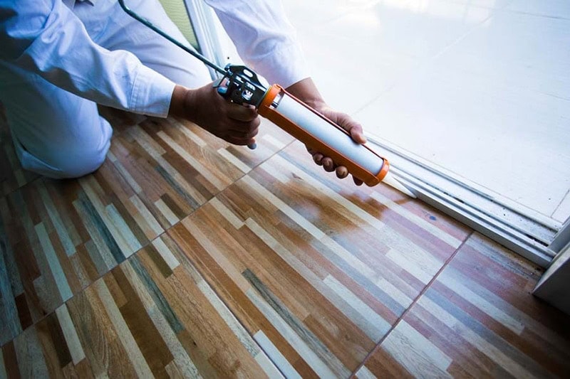 Construction workers install doors - windows and use silicon and sealant