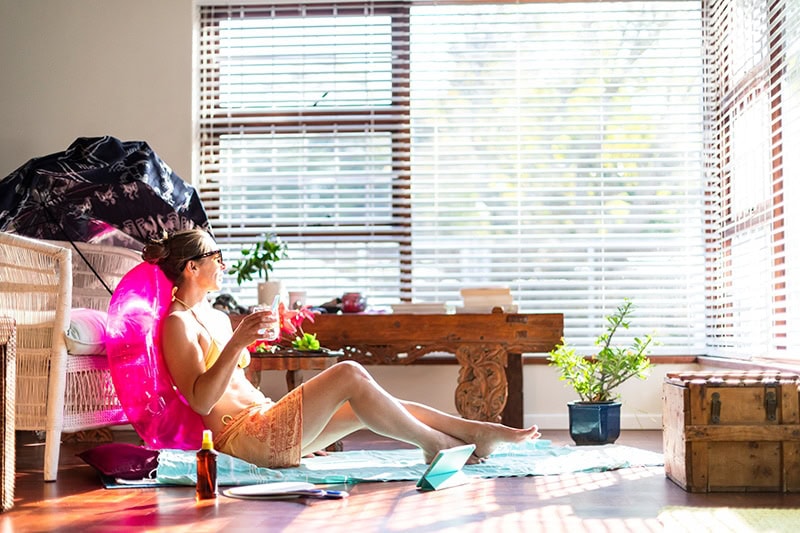 woman sitting in her apartment on a beach towel with a pool inflatable.