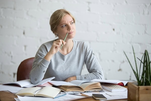 Woman sitting at her desk trying to notice the signs telling her she needs a new furnace.