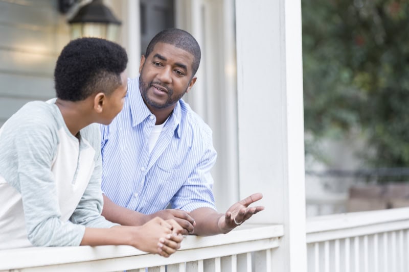 How Does a Gas Furnace Work? Father talking to his son outdoors on a patio.