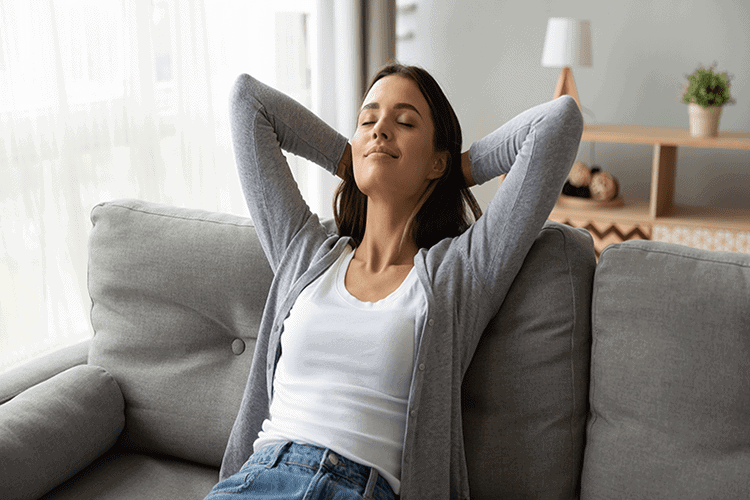 Blog Title: Why Do I Need a Humidifier? Photo: woman breathing easy on a coach