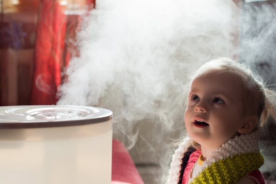 little girl looking at the humidifier in her home