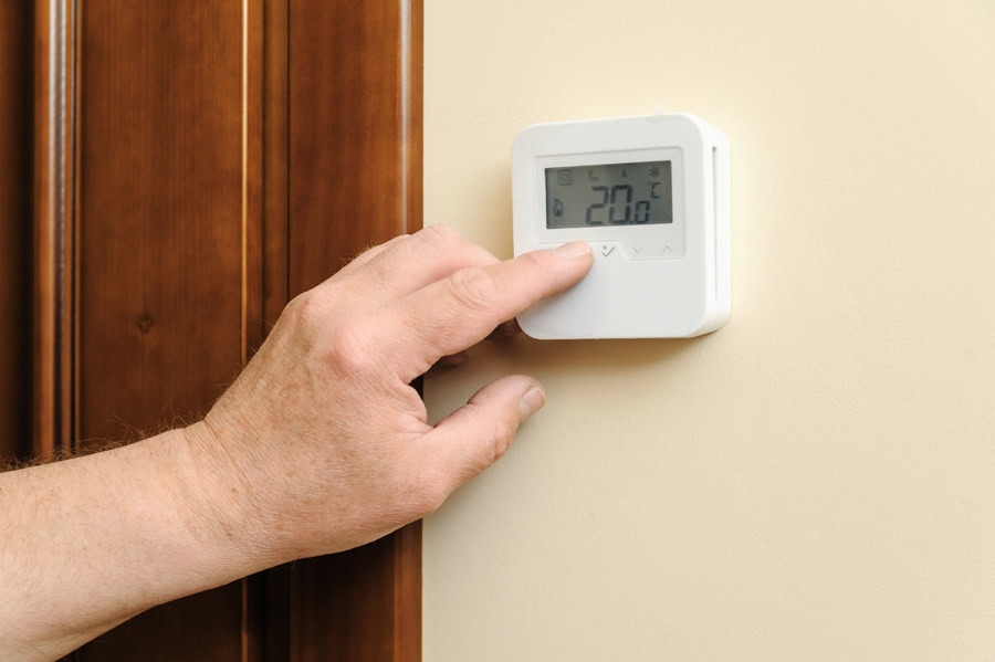 Man is changing settings of a thermostat. Man is changing settings of a thermostat.