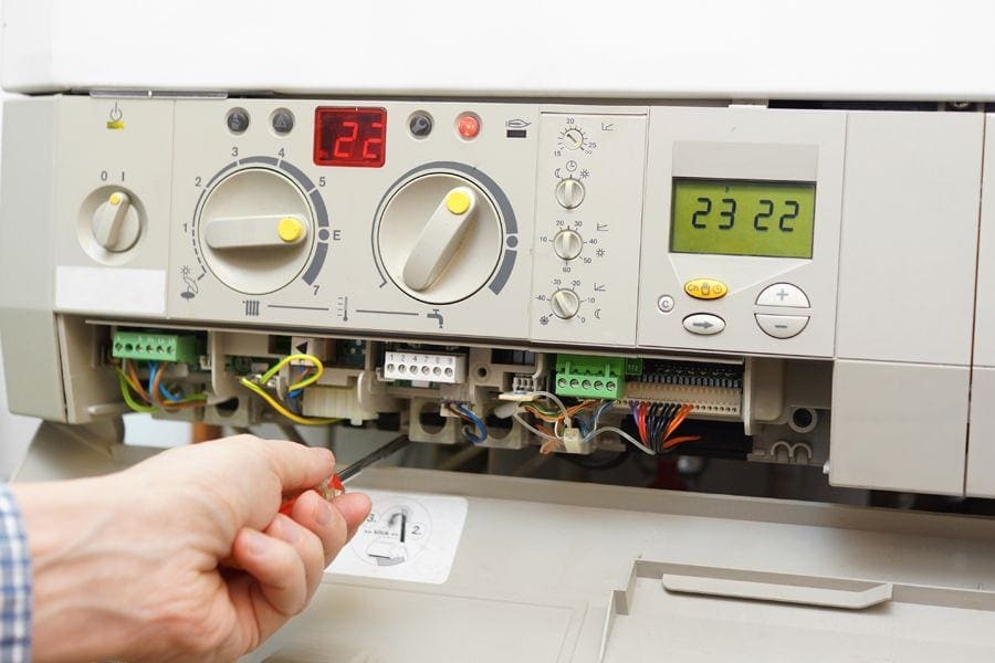 Someone working on furnace with screw driver. When should you replace your furnace?