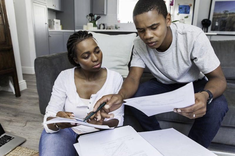 Couple Looking Over Bills trying to determine how to afford a new AC system and other HVAC equipment for their home.