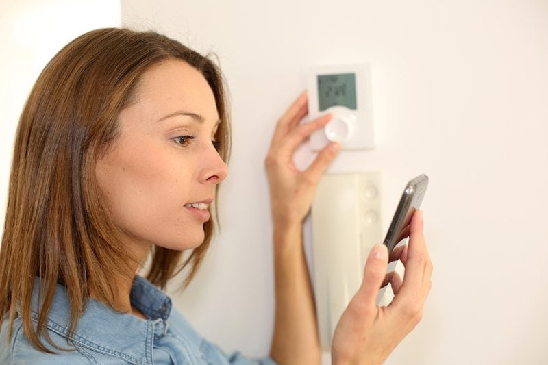Woman regulating furnace fan setting.