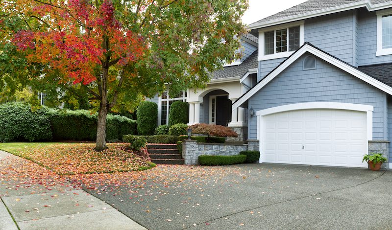 Driveway to front walkway view of partial front of residential home during early autumn season
